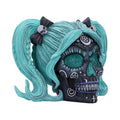 Skull figurine with teal hair and black bows on a white background