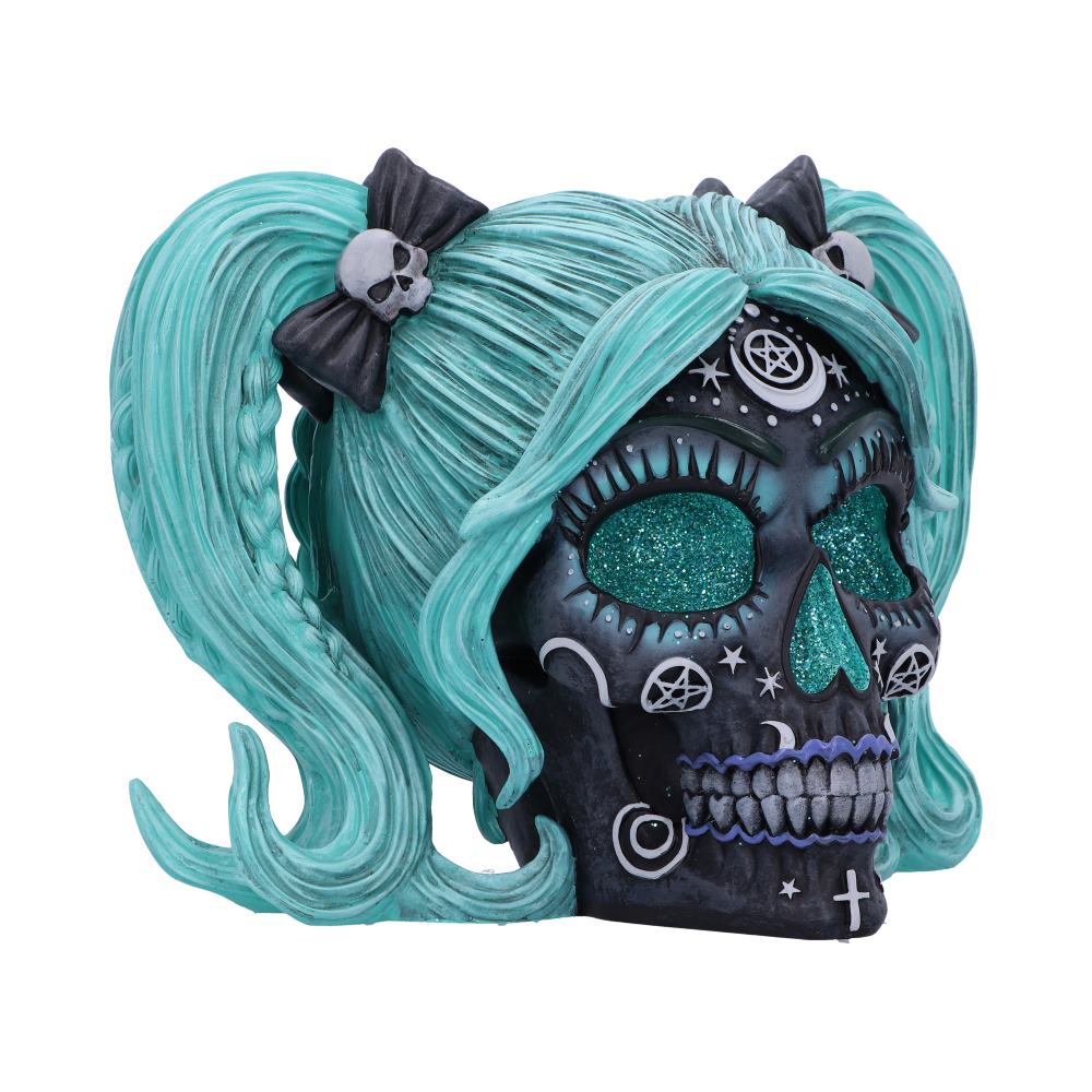Skull figurine with teal hair and black bows on a white background