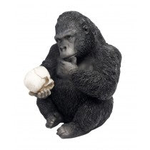 Statue of a gorilla holding a coconut on a white background