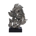 Decorative metal leaf sculpture on a black base against a white background