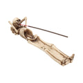 Skeletal figure holding incense sticks on a white background mystic cave